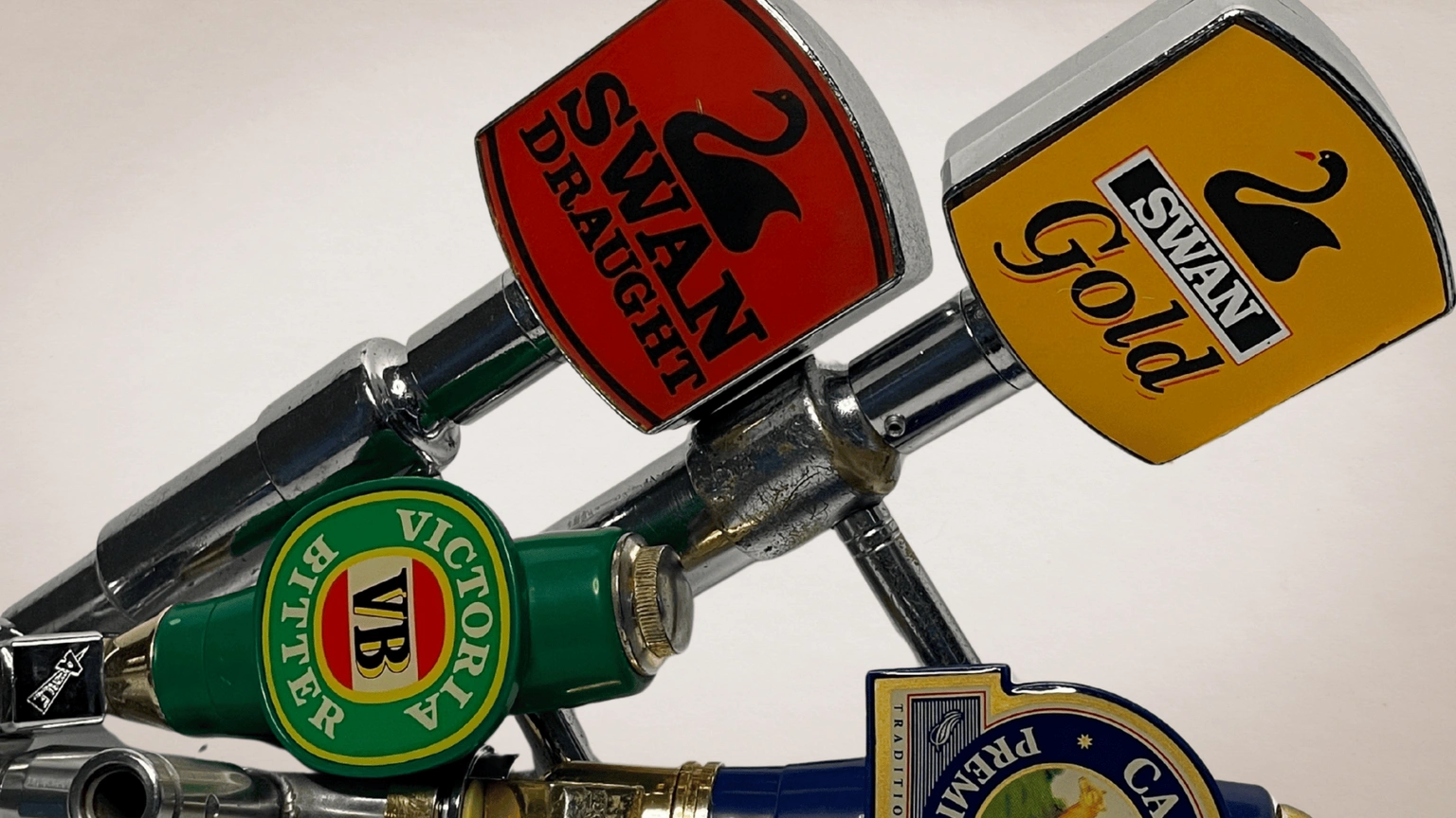Close-up of vintage beer tap handles including Swan Draught, Swan Gold and Victoria Bitter